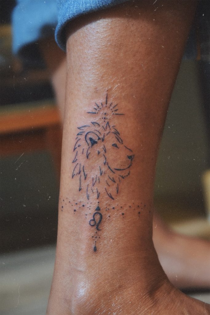 Tatouage d'un lion sur la cheville, avec des ornements.