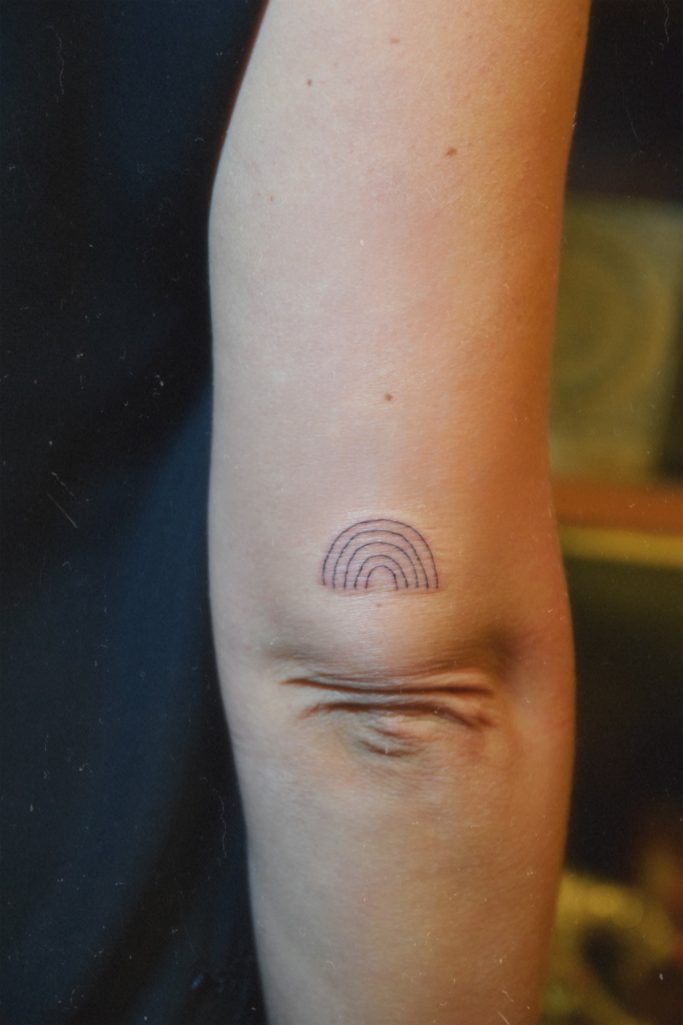 Tatouage au dessus coude représentant un un arc-en-ciel.