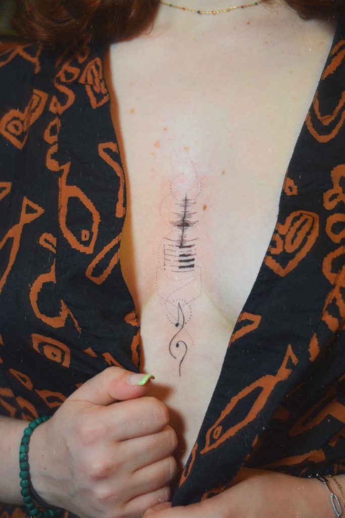 Tatouage underboob au thème de la musique.