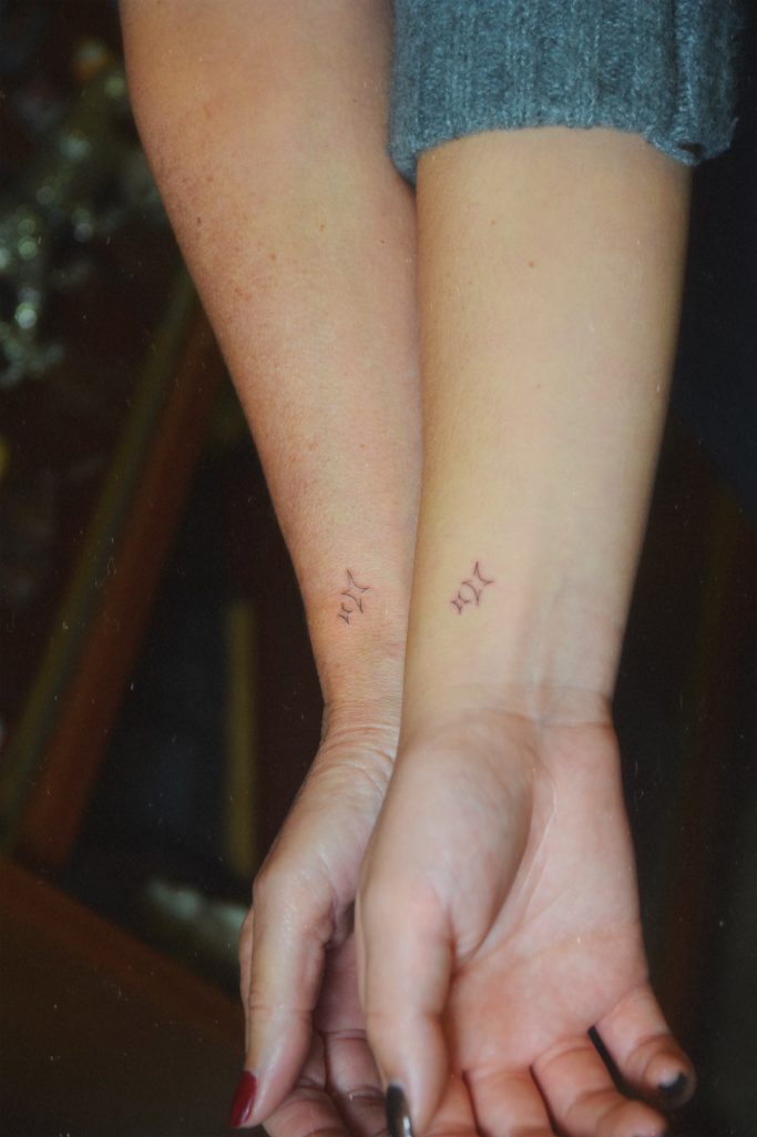 Deux bras avec des tatouages discrets en forme d'étoile sur les poignets.