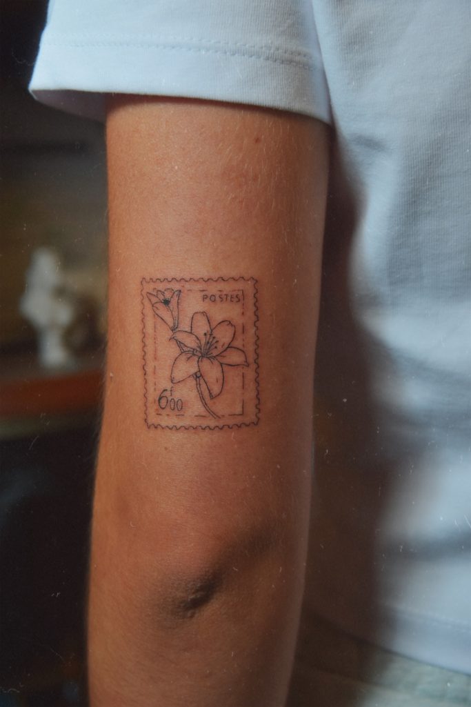 Tatouage d'un timbre floral sur le bras d'une personne.