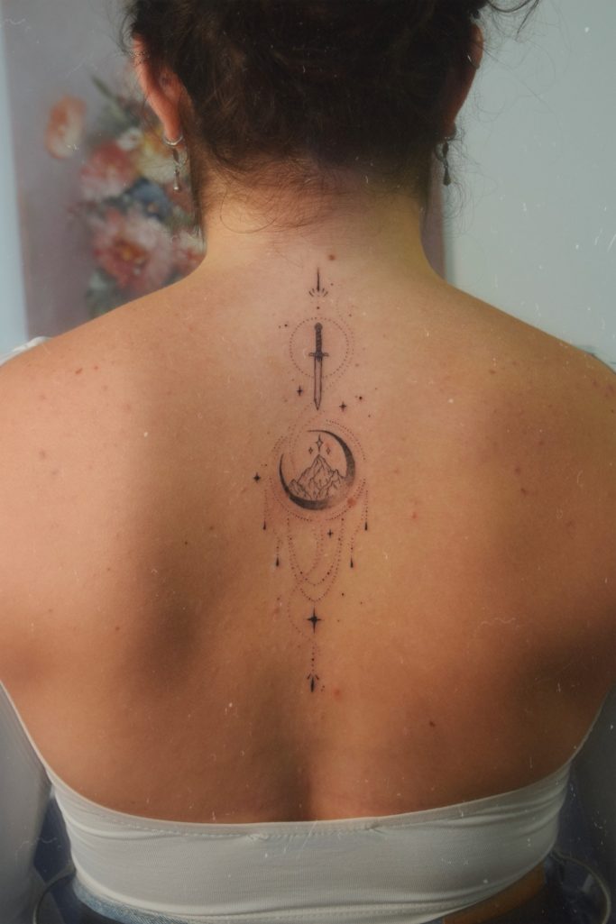 Tatouage dans le dos représentant une lune, des montagnes des étoiles et de l'ornement.