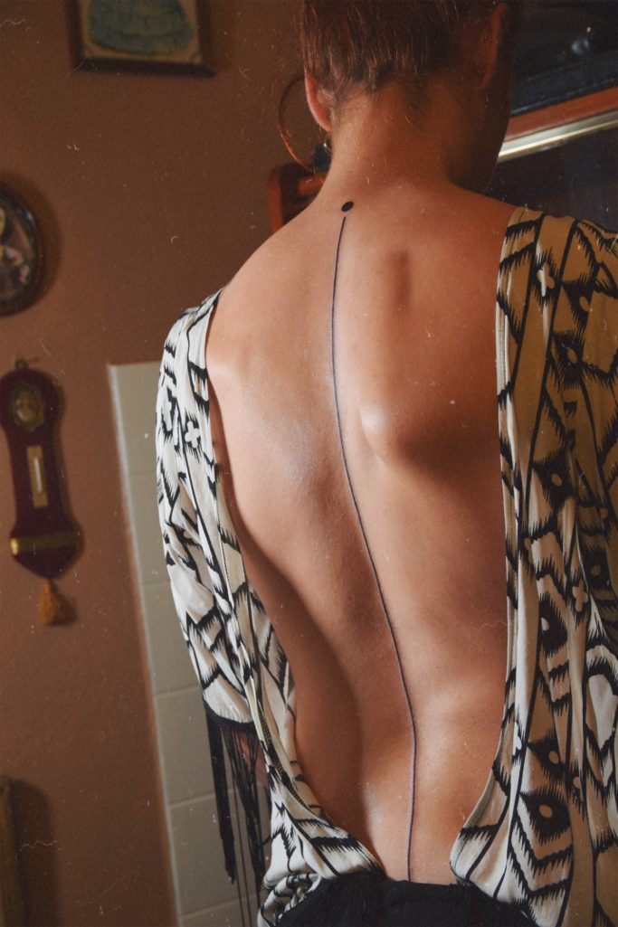 Tatouage d'une ligne noire qui traverse le dos.