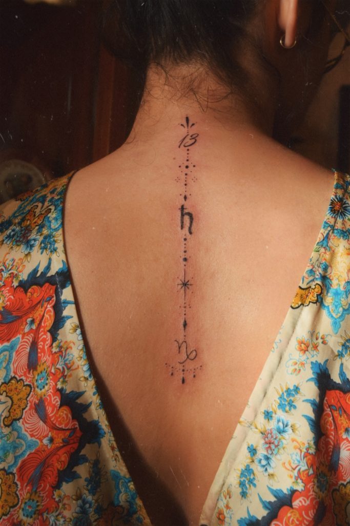 Tatouage délicat sur le haut du dos, avec des motifs ornementaux.
