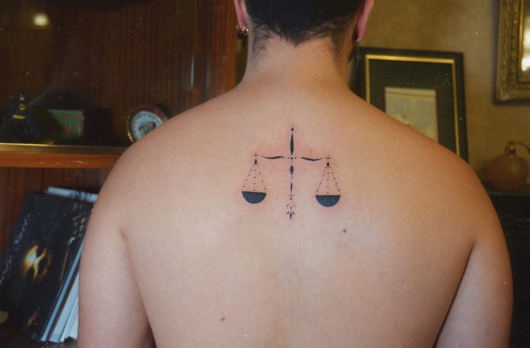 Tatouage d'une balance sur le dos d'une personne.