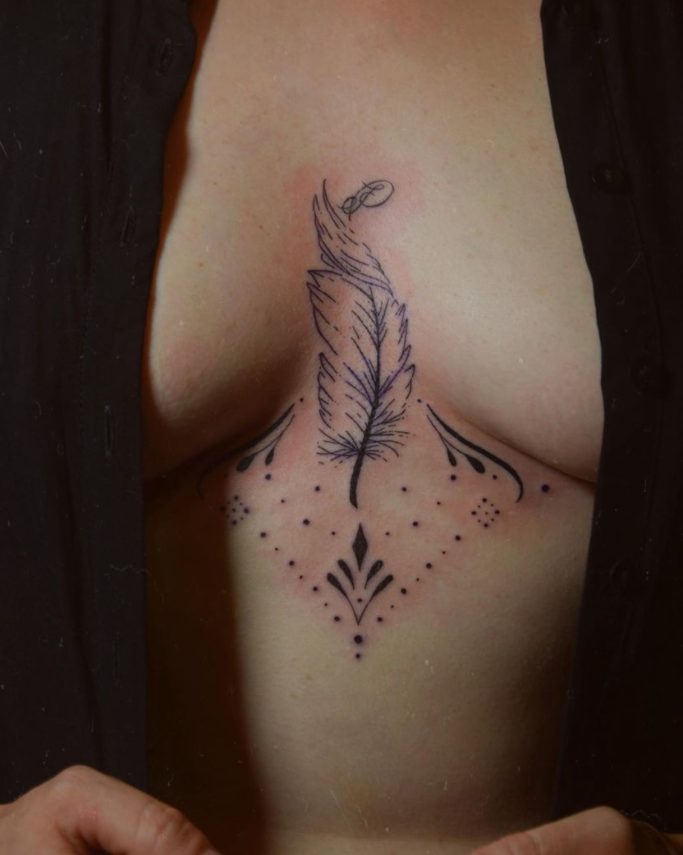 Tatouage de plume avec motifs géométriques sur la poitrine.