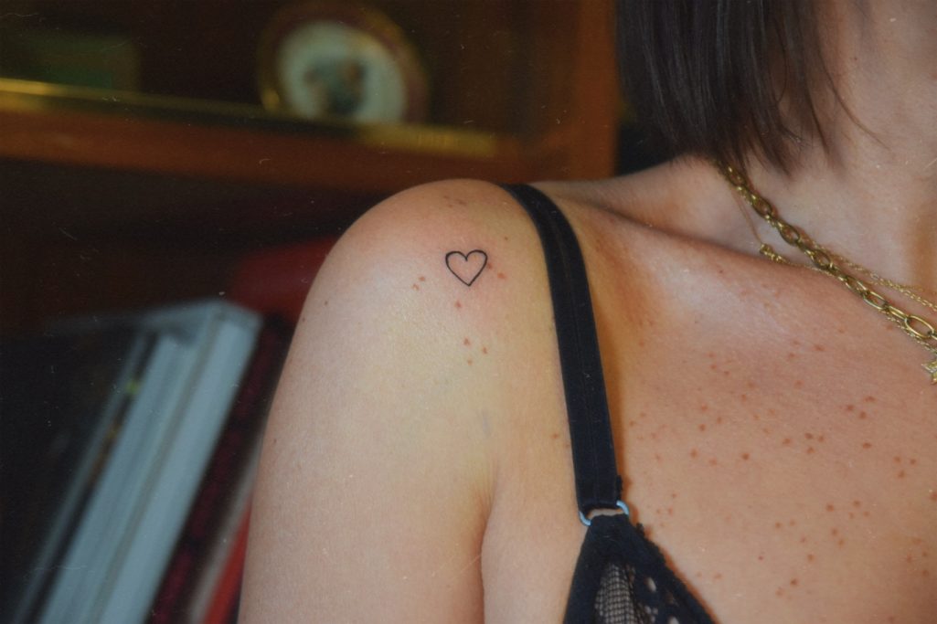 Un petit tatouage en forme de cœur sur l'épaule d'une personne.
